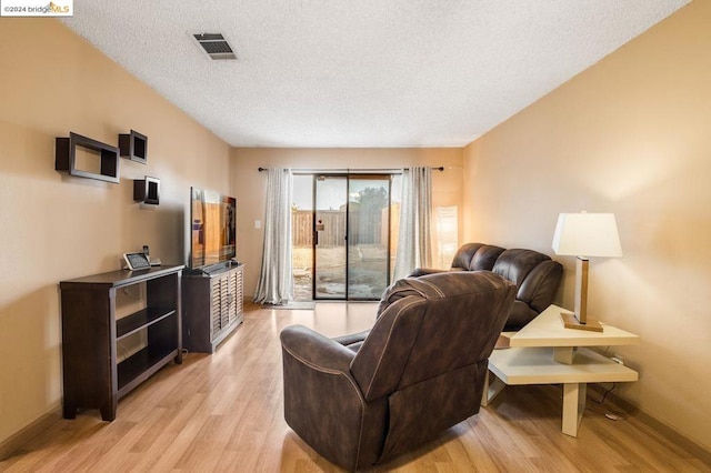 living room with a textured ceiling and light hardwood / wood-style flooring