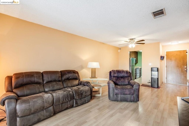 living room with ceiling fan, light hardwood / wood-style floors, and a textured ceiling