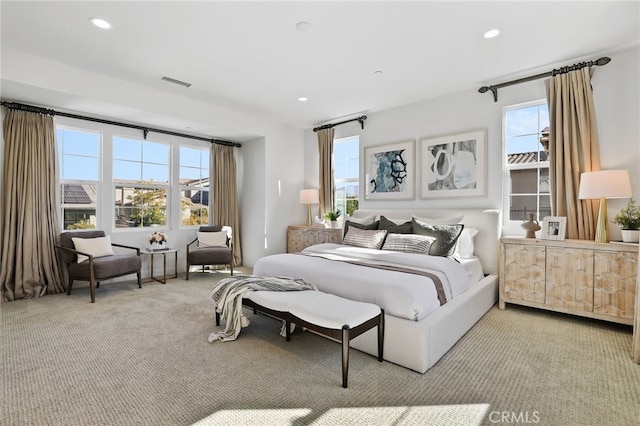 bedroom with light colored carpet and multiple windows