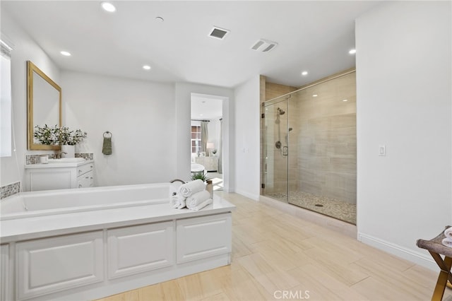 bathroom featuring vanity and independent shower and bath