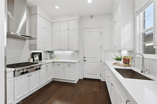 kitchen with stainless steel gas stovetop, dark wood-type flooring, white cabinets, wall chimney range hood, and sink