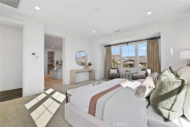 bedroom with connected bathroom and light hardwood / wood-style flooring