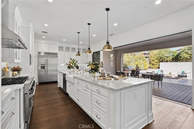 kitchen featuring white cabinets, a wealth of natural light, high end appliances, and a kitchen island with sink