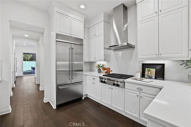 kitchen with white cabinets, stainless steel appliances, dark hardwood / wood-style floors, and wall chimney exhaust hood