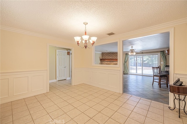 unfurnished dining area with a textured ceiling, light tile patterned floors, ceiling fan with notable chandelier, and ornamental molding