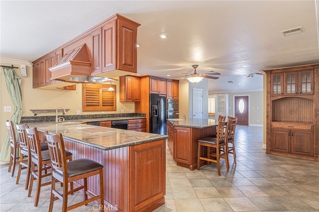 kitchen featuring black appliances, ceiling fan, a kitchen island, a kitchen bar, and kitchen peninsula