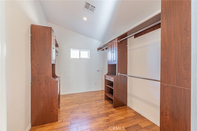 spacious closet featuring light hardwood / wood-style floors and lofted ceiling