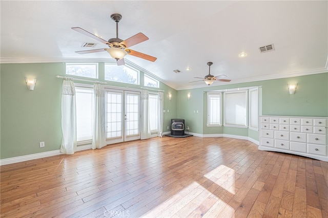 unfurnished living room featuring a wood stove, crown molding, and light hardwood / wood-style floors