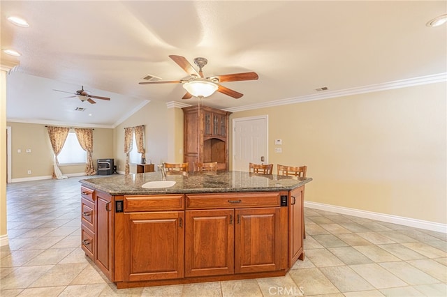 kitchen with crown molding, a center island, dark stone counters, and sink