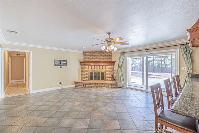 unfurnished living room featuring ceiling fan, a fireplace, a textured ceiling, and ornamental molding