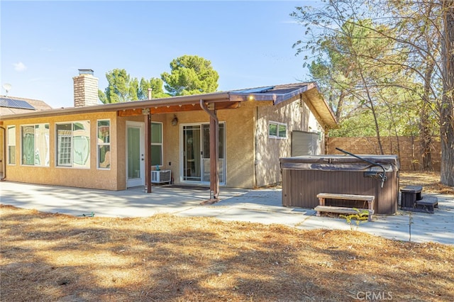 rear view of property with a patio, a hot tub, and cooling unit