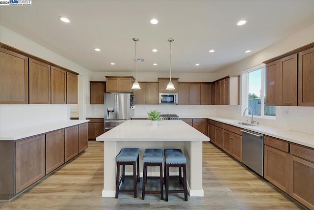 kitchen with light hardwood / wood-style flooring, a kitchen island, stainless steel appliances, and sink