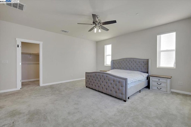 carpeted bedroom featuring a closet, a spacious closet, multiple windows, and ceiling fan