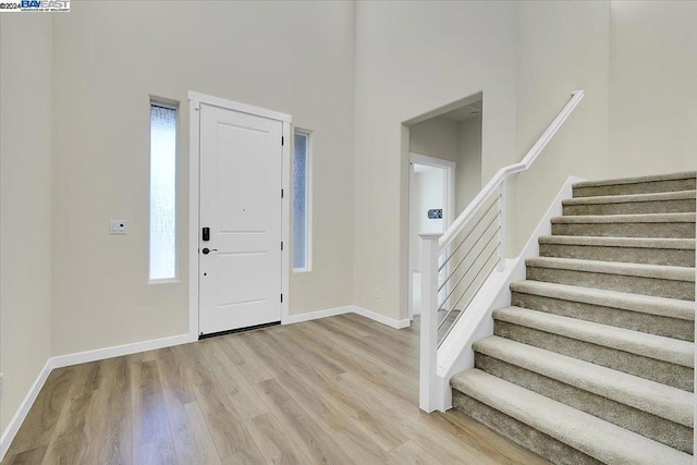 entrance foyer with wood-type flooring and a towering ceiling