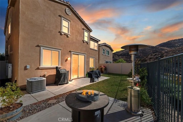 back house at dusk with a patio, a mountain view, cooling unit, and an outdoor fire pit