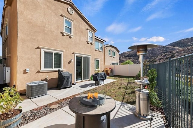 back of property with a mountain view, a patio area, central air condition unit, and an outdoor fire pit