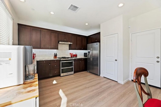 kitchen with dark brown cabinetry, stainless steel appliances, light hardwood / wood-style floors, and decorative backsplash