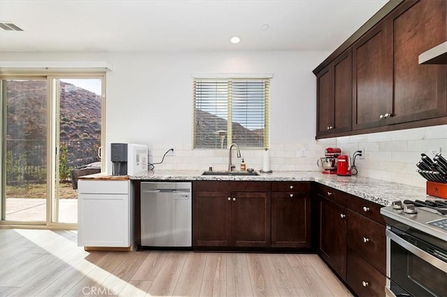 kitchen featuring stainless steel appliances, tasteful backsplash, sink, and light stone counters