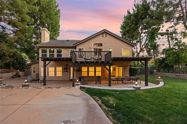 back house at dusk with a lawn, a pergola, a patio, and a wooden deck