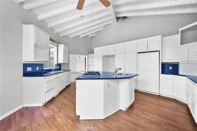 kitchen featuring beam ceiling, sink, a center island with sink, white cabinets, and hardwood / wood-style flooring