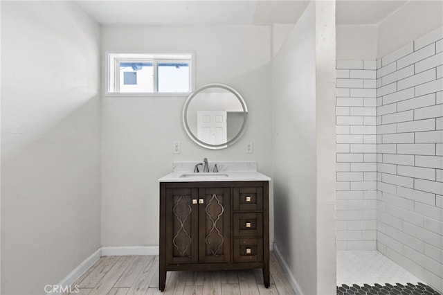 bathroom with hardwood / wood-style floors, vanity, and tiled shower