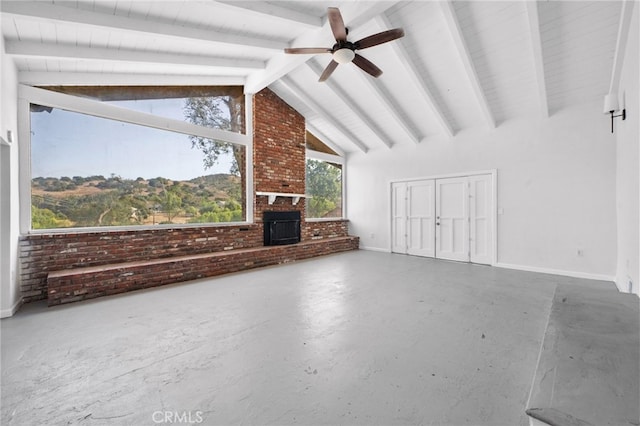 unfurnished living room featuring ceiling fan, lofted ceiling with beams, brick wall, concrete floors, and a fireplace