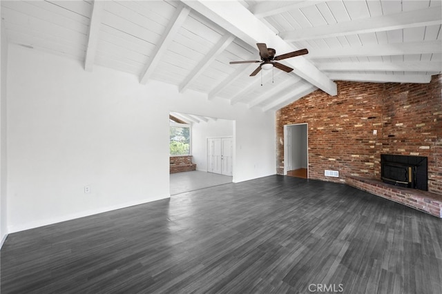 unfurnished living room featuring vaulted ceiling with beams, ceiling fan, dark wood-type flooring, and brick wall