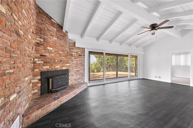 unfurnished living room featuring beam ceiling, a wood stove, ceiling fan, dark hardwood / wood-style flooring, and brick wall