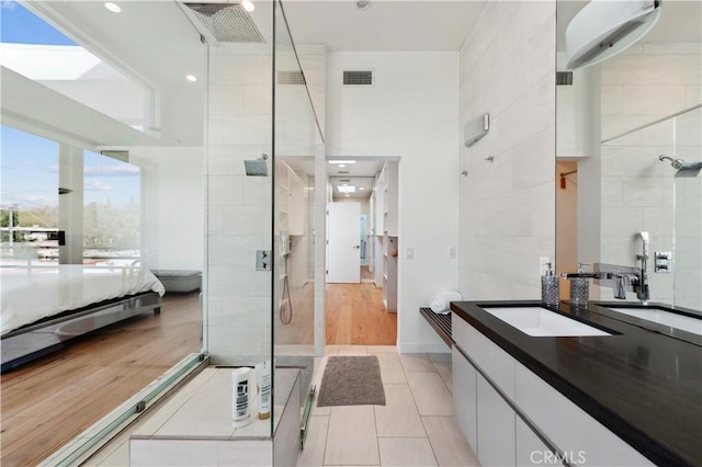 bathroom with hardwood / wood-style floors, vanity, and tiled shower