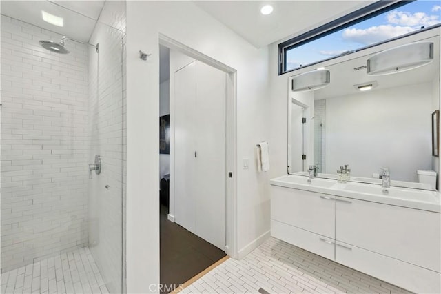 bathroom with a tile shower and vanity