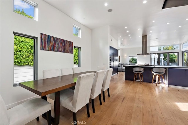 dining space with light hardwood / wood-style flooring and a high ceiling