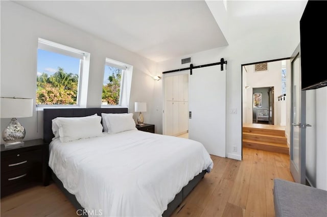 bedroom with a barn door and light hardwood / wood-style flooring