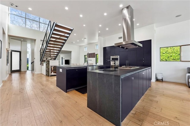 kitchen with a large island, light hardwood / wood-style flooring, and island range hood