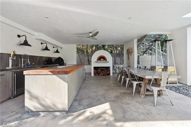 view of patio with a fireplace, area for grilling, ceiling fan, and a wet bar