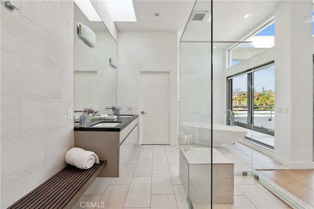 bathroom featuring a skylight, tile patterned flooring, a towering ceiling, vanity, and independent shower and bath