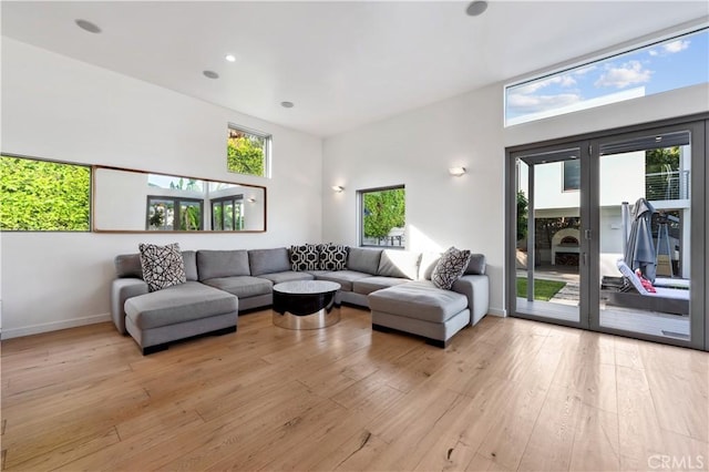 living room with a towering ceiling, light hardwood / wood-style flooring, and plenty of natural light