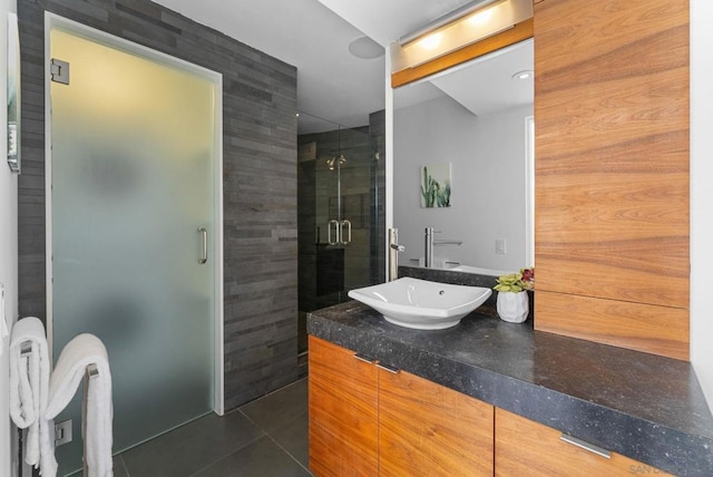 bathroom with a shower with door, vanity, and tile patterned flooring