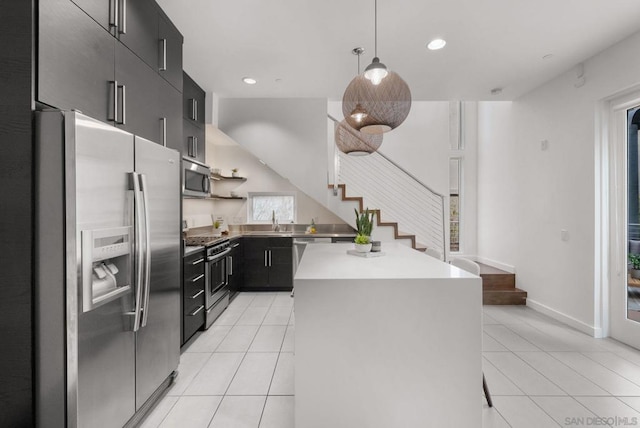 kitchen with appliances with stainless steel finishes, sink, light tile patterned floors, a center island, and hanging light fixtures