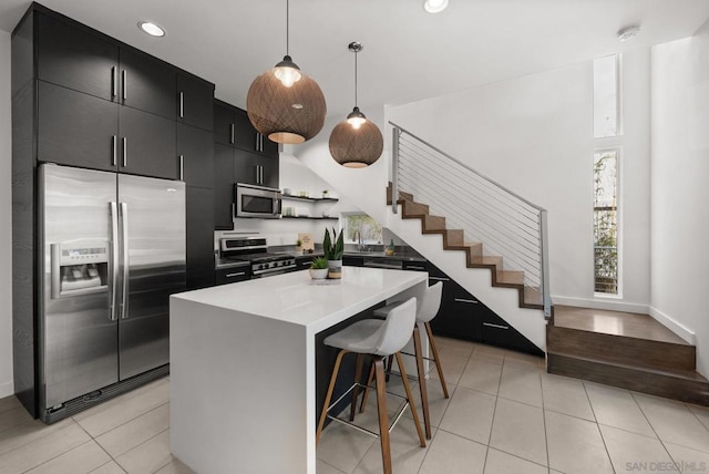 kitchen with a center island, a kitchen breakfast bar, decorative light fixtures, light tile patterned floors, and appliances with stainless steel finishes