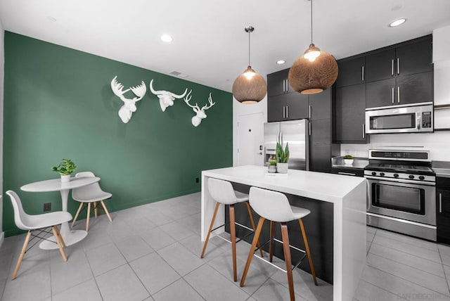 kitchen featuring pendant lighting, light tile patterned flooring, a kitchen island, a kitchen bar, and stainless steel appliances