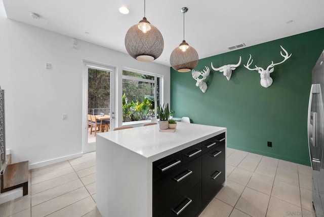 kitchen featuring pendant lighting, a center island, light tile patterned floors, and stainless steel refrigerator