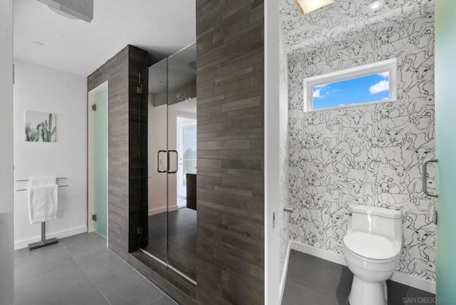 bathroom featuring tile patterned floors, toilet, a shower with shower door, and tile walls