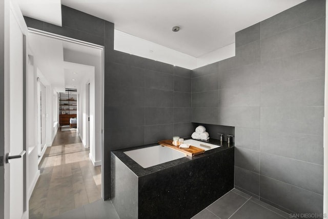 bathroom featuring tile patterned flooring, tile walls, and a tub