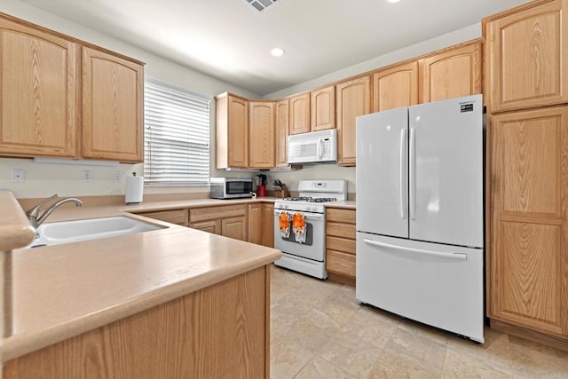 kitchen featuring light brown cabinetry, white appliances, and sink