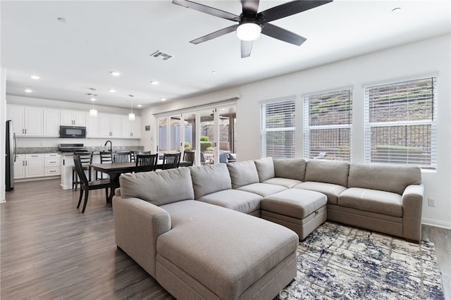 living room featuring ceiling fan and dark wood-type flooring