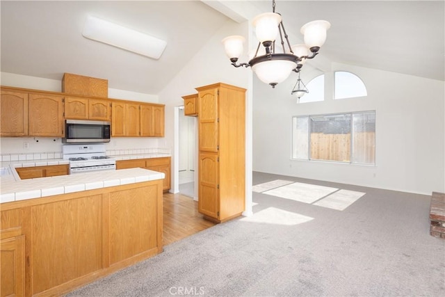 kitchen featuring lofted ceiling, tile counters, hanging light fixtures, and white range