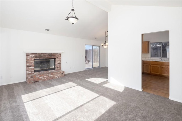 unfurnished living room featuring dark carpet, sink, a fireplace, and vaulted ceiling