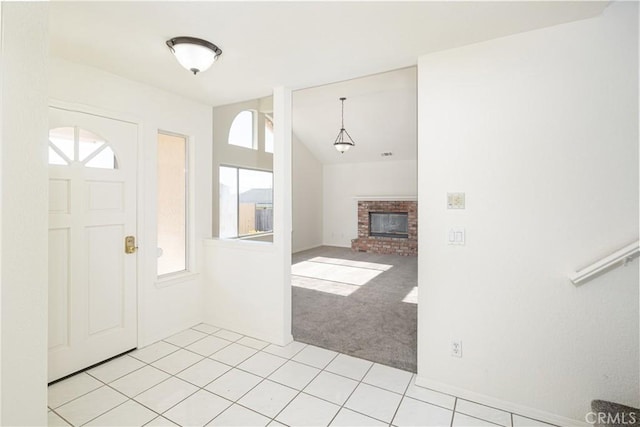 carpeted foyer entrance featuring vaulted ceiling, a brick fireplace, and a healthy amount of sunlight