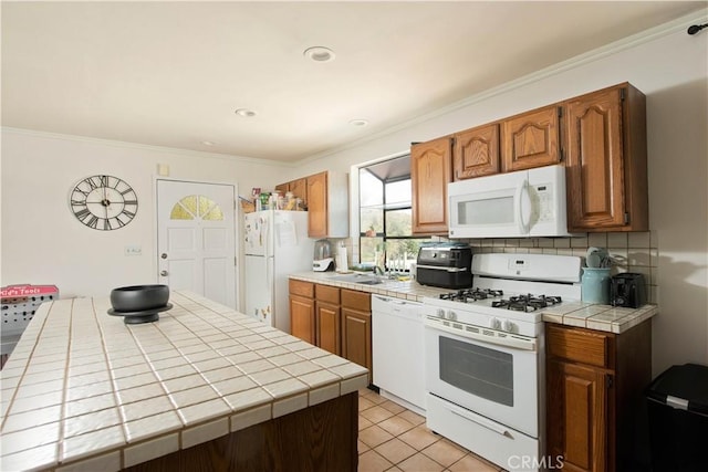 kitchen featuring tasteful backsplash, tile countertops, white appliances, light tile patterned floors, and ornamental molding