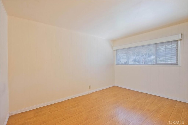 empty room featuring wood walls and light wood-type flooring